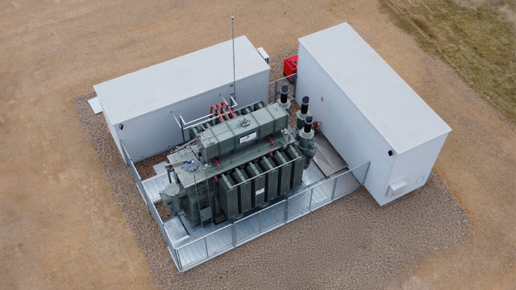 Vista aérea de subestación compacta prefabricada con transformador de potencia y dos módulos técnicos laterales